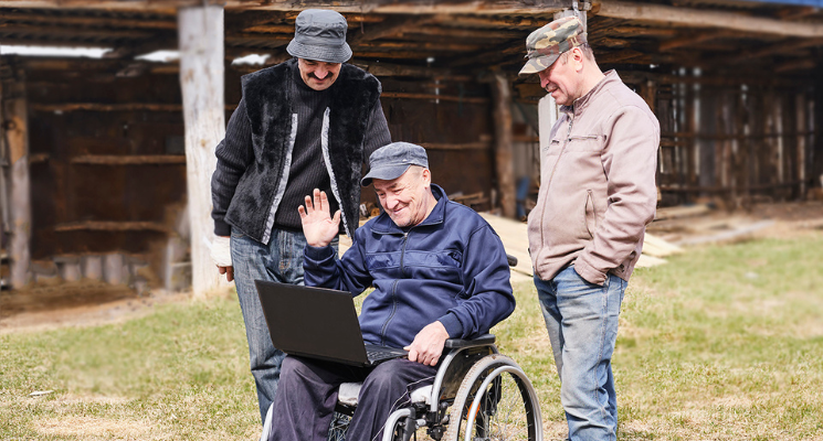 Senior man on wheelchair looking laptop in a yard